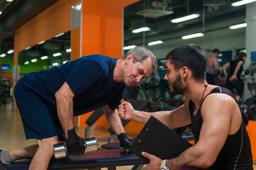 Senior man doing weight exercise with trainer.