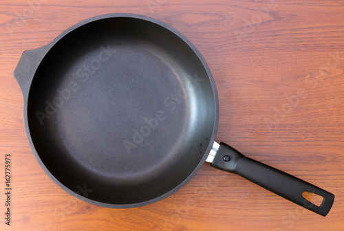 Fotografie, Obraz Frying pan.
Closeup of a black frying pan on wooden background.