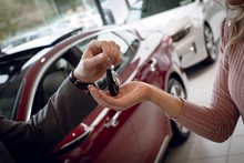 Close Up Of Salesman Giving Car Keys To Female Customer