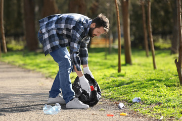 Young volunteer picking up litter in park