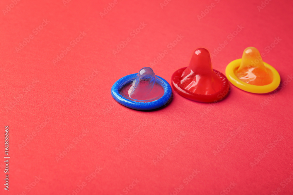 Colorful condoms on red background. Safe sex concept