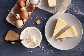 Canvas Print - Pieces of delicious cheese cake with ingredients on kitchen table