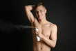 © Africa Studio - Handsome young man with deodorant on dark background