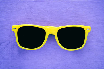 Wall Mural - Hipster yellow sunglasses on purple wooden background