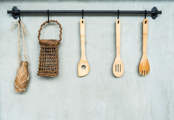 The wooden kitchenware hanging on the black metal hanger on the gray wall.