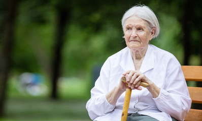 Wall Mural - Senior woman sitting on bench in summer park