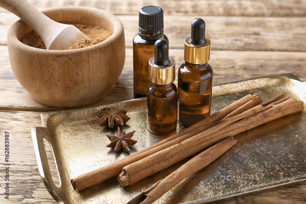 Composition with bottles of cinnamon oil on wooden background