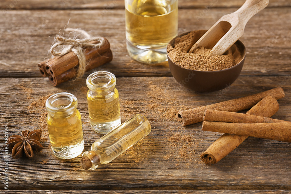 Composition with bottles of cinnamon oil on wooden background