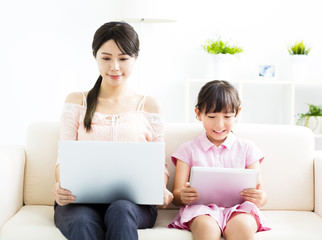 Canvas Print - mother with  daughter looking at Laptop  on sofa