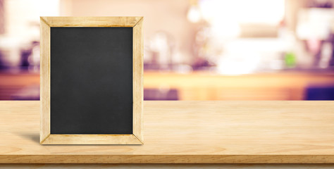 Poster - Blank blackbaord on plank wooden table top with blurred home kitchen,Mock up template for display or montage of your design,Banner for advertise of product,panorama view.