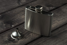 Metall Hip Flask With Cup On Wooden Backdrop
