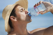 homme à la plage qui boit de l'eau minérale avec une bouteille