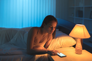 Wall Mural - The attractive woman phone in the bed. night time