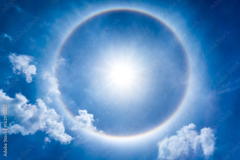 The storng sun halo at noon time on the blue sky and cumulus clouds - obrazy, fototapety, plakaty 