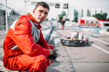 Poster - Karting racer sits on a tire, kart on background