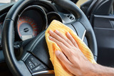 Fototapeta Przestrzenne - Hand cleaning car steering wheel with microfiber cloth, auto detailing concept
