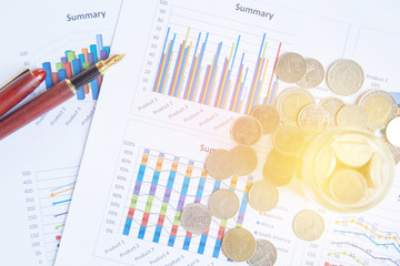 graph, chart and pen with stacks of coins