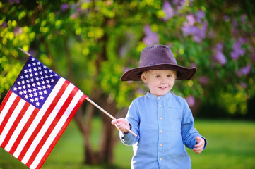 Wall Mural - Cute toddler boy holding american flag in beautiful park