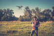 © scaliger - Man operating drone quad copter in park, vintage style photo