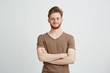 © Cookie Studio - Portrait of happy cheerful young man with beard smiling looking at camera with crossed arms over white background.