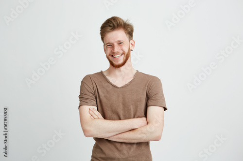 Portrait of happy cheerful young man with beard smiling looking at camera with crossed arms over white background Tableau sur Toile