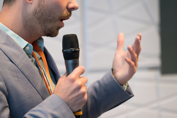 Speaker at conference holding microphone in the hand