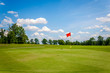 Golf course with beautiful green grass, bright blue skies and white puffy clouds.  Recreational sporting activity of golf.