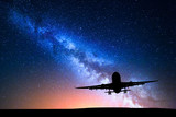 Fototapeta Na sufit - Milky Way and silhouette of a airplane. Landscape with passenger airplane is flying in the starry sky at night. Space background. Commercial airliner on the background of colorful Milky Way. Aircraft