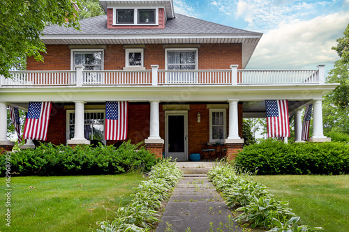 Fotografija American flag decorations on front porch of old brick home