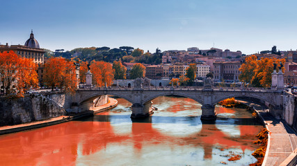 Skyline with bridge Ponte Vittorio Emanuele II and classic architecture in Rome, Vatican City scenery over Tiber river. Autumn view with red foliage.