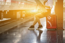 Beautiful Young Woman Sitting In The Train Station Waiting A Train With Red Luggage And Baggage On A Platform Trolley While Open Map For Finding Place In The Morning,vintage Color,selective Focus,