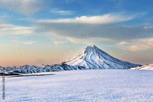 Plakat Viluchinskiy wulkan (kamchatka, rosja) na zachód słońca z różowym niebem na daleko