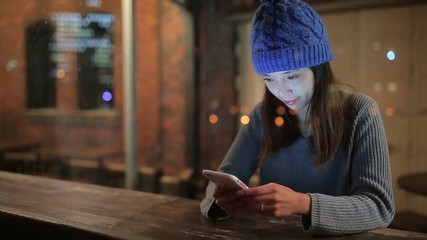 Wall Mural - Woman using cellphone at night inside coffee shop