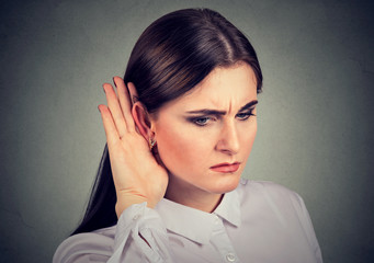 Curious woman with hand to ear carefully listening to gossip conversation