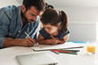 © BalanceFormCreative - Young father teach his daughter to draw. They're sitting at the table in the living room. Natural light ambient.