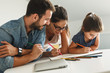 © BalanceFormCreative - Father and mother teach daughter to draw. They're sitting in the living room. Natural light ambient.