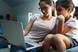 © BalanceFormCreative - Mother and daughter watching something on laptop. They're sitting by the window in the living room.