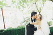 © olegparylyak - Romantic, fairytale, happy newlywed couple hugging and kissing in a park, trees in background