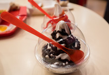 Focus On Chocolate Soft Ice Cream In The Plastic Cup With Red Spoon