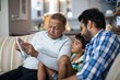 © WavebreakMediaMicro - Grandfather showing tablet to grandson sitting with father at ho