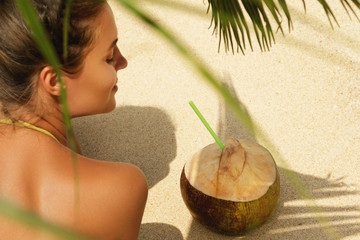 Wall Mural - Woman with coconut drink under palm leaf