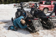 Man Repairing Snowmobile On A Sunny Day