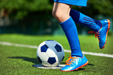 Legs Football Player Boy In Boots With Ball On Grass