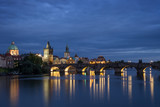 Fototapeta Londyn - Lit Charles Bridge (Karluv most) and old buildings at the Old Town and their reflections on the Vltava River in Prague, Czech Republic, at dusk. Copy space.