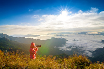 Photographers are using cameras take photo  Beautiful landscapes views mountains covered by foggy with sunlight in the blue sky and clouds. Phu Chi Fa, Chiang Rai Province, Thailand