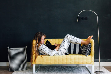 Pre teen child on the couch against black wall in modern living room interior