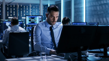 Aufkleber - Close-up of Technical Engineer Working on His Computer With Multiple Displays in Monitoring Room. In the Background His Colleagues with Graphics and Various Data on Their Monitors.
