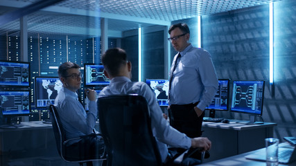 Wall Mural - Team of Technical Moderators Have Discussion in Monitoring Room. System Control Room is full of Working Displays and Has Servers Racks.