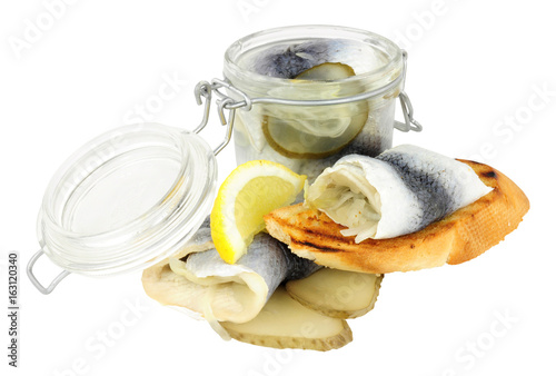 Fotografie, Obraz Pickled rollmop herrings in a glass storage jar and toasted bread isolated on a