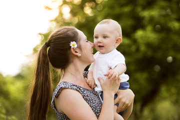 Young mother in nature holding little baby son in the arms.